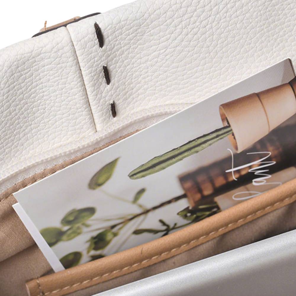 White tote bag with front zipper pocket and brown leather tassel, practical design for organizing small items.