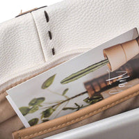 White tote bag with front zipper pocket and brown leather tassel, practical design for organizing small items.