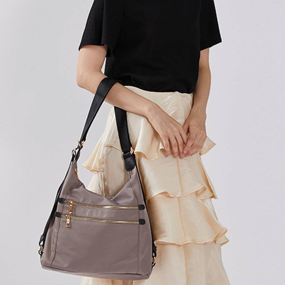 Gray nylon hobo crossbody bag worn by a model, adjustable shoulder strap, casual everyday fashion for work and travel.