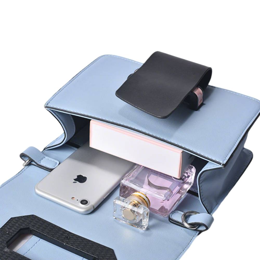 Open light blue crossbody bag showing interior space, holding a smartphone, perfume bottle, and small box, demonstrating spacious capacity.