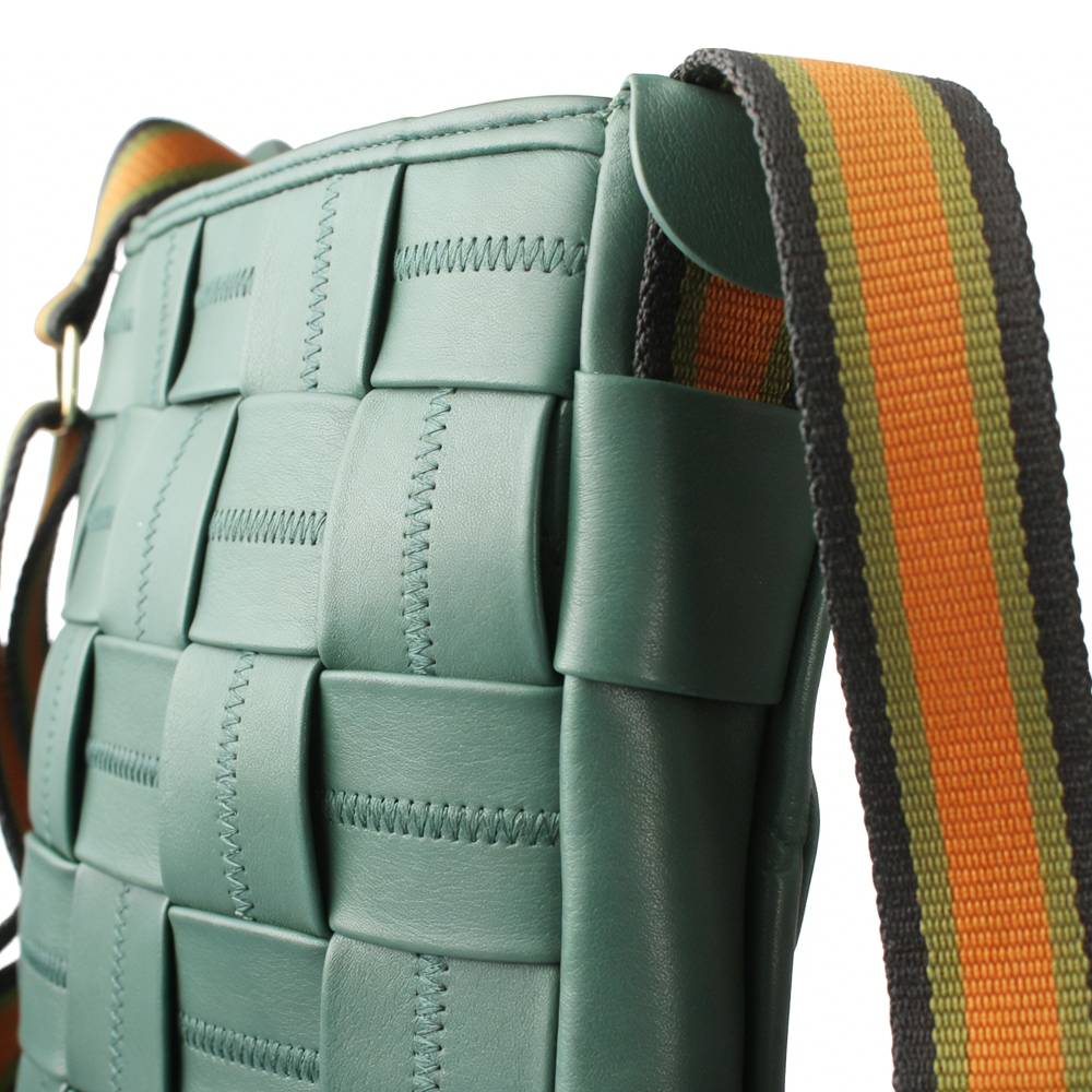 Close-up of a teal woven leather crossbody bag, emphasizing the precise decorative stitching on the woven leather panels.