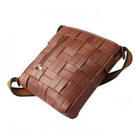Angled side view of a brown woven leather crossbody bag, displaying the front zippered pocket and textured woven pattern.