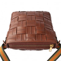 Bottom view of a brown woven leather crossbody bag, highlighting the gold zipper closure and detailed woven craftsmanship.