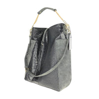 Close-up of gray crocodile-embossed leather panel with suede-like side pocket, demonstrating mixed-material durability.