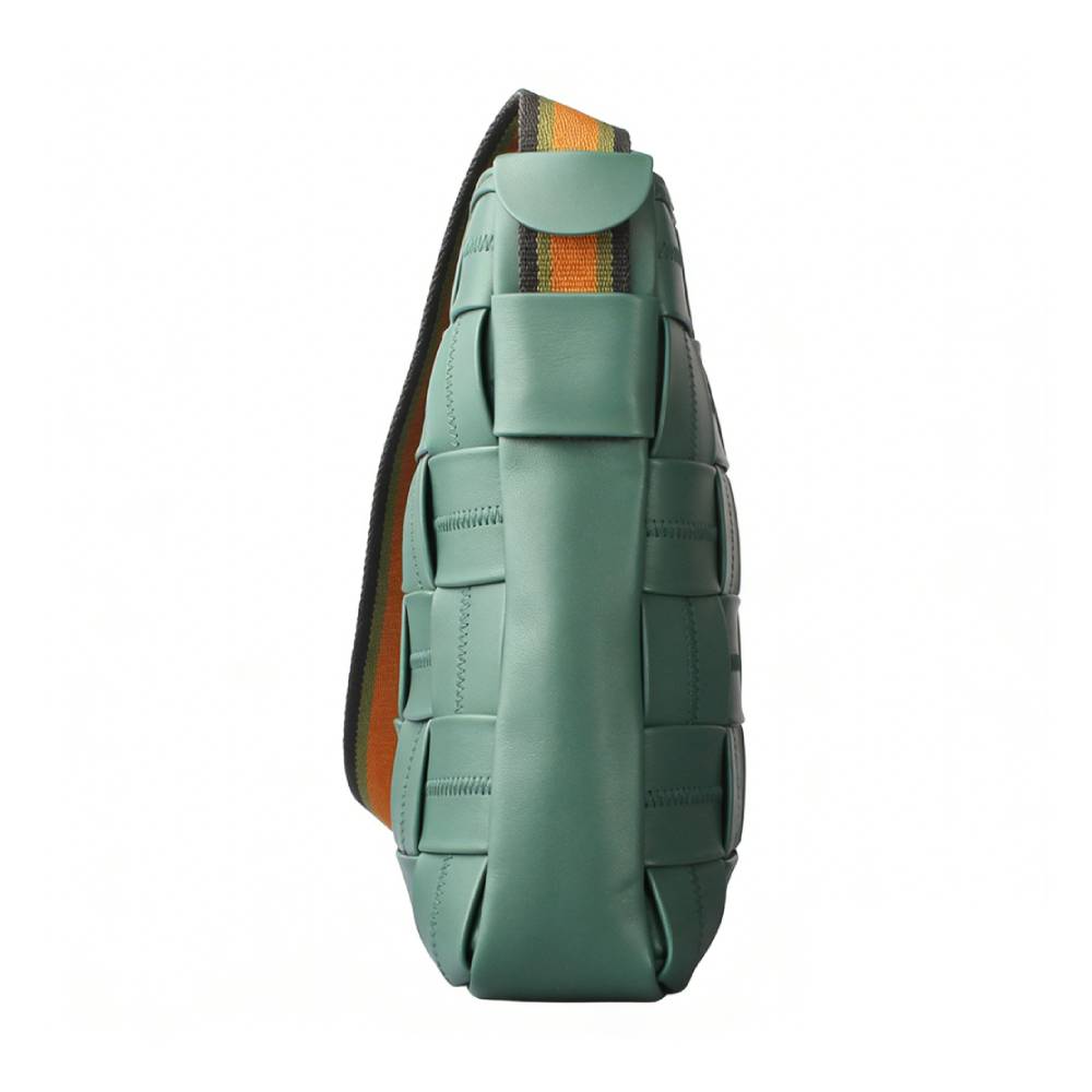 Side view of a teal woven leather crossbody bag, showcasing a checkered woven pattern with decorative stitching and a striped shoulder strap.