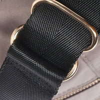 Close-up of adjustable black shoulder strap with gold metal rings on gray nylon crossbody bag, highlighting sturdy construction.