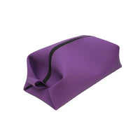 Angled view of a purple toiletry bag with black rubberized zipper and smooth finish, ideal for compact storage of travel essentials.