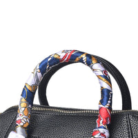 Close-up of the handbag’s top handle wrapped in a colorful nautical-patterned silk scarf, showcasing decorative design and elegant detailing.