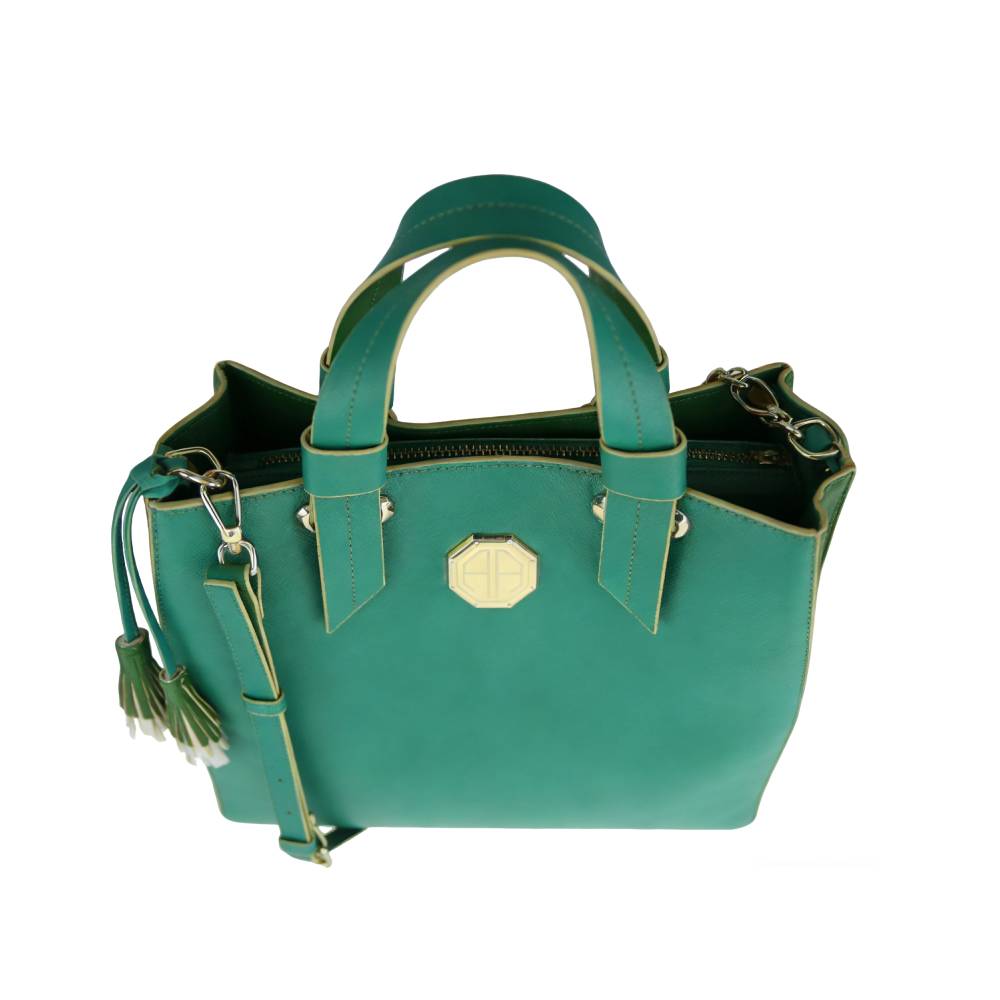 Close-up of teal green leather bag with gold octagonal emblem and contrast stitching, highlighting premium material and craftsmanship.