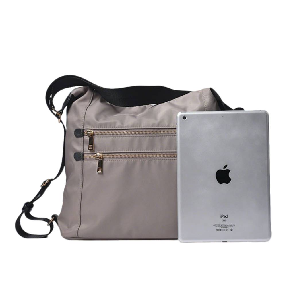 Gray nylon hobo bag next to an iPad, showing spacious capacity to fit a tablet, ideal for work and travel.