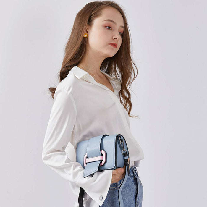 Model wearing a light blue leather crossbody bag with pink geometric buckle, casual fashion style for everyday use.