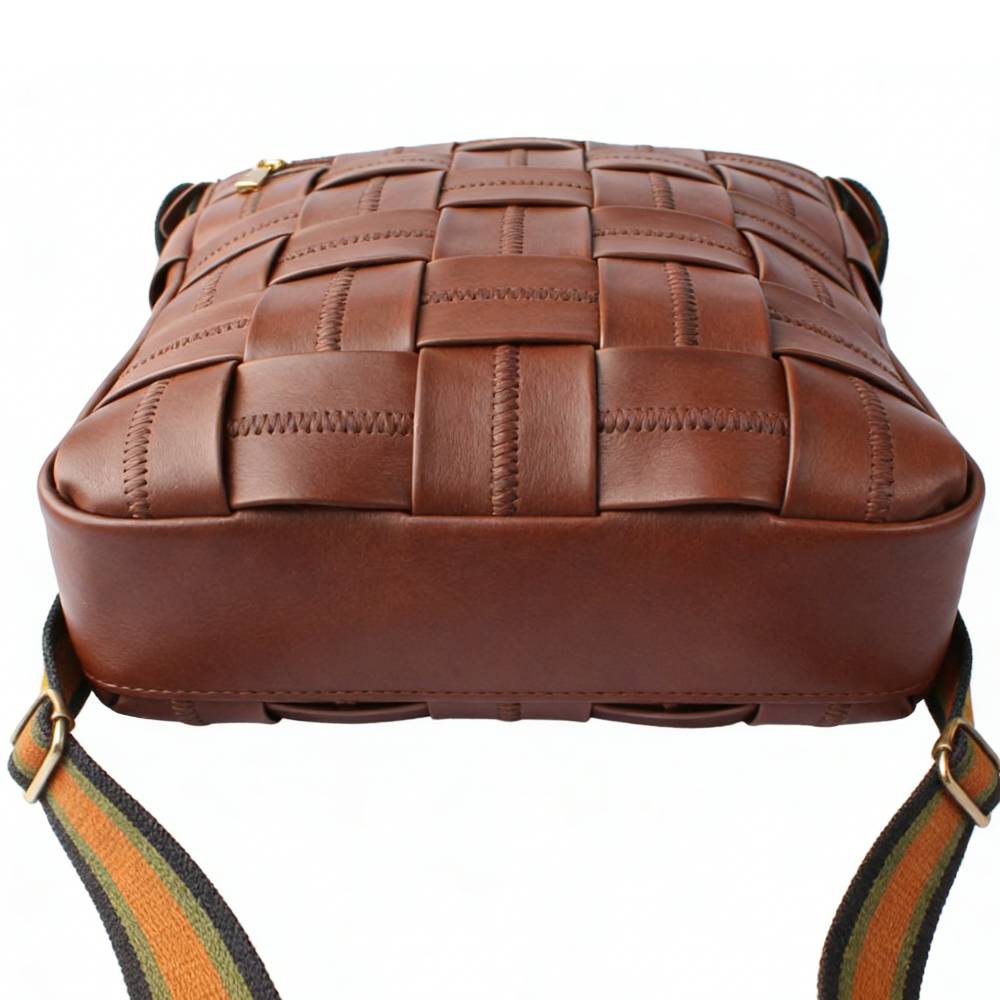 Side view of a brown woven leather crossbody bag, featuring a checkered pattern with decorative stitching and a striped adjustable shoulder strap.