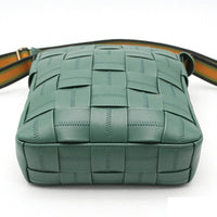 Bottom view of a teal woven leather crossbody bag, highlighting the detailed checkered woven pattern and reinforced base stitching.