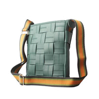 Back view of a teal woven leather crossbody bag, showing the adjustable striped shoulder strap with gold metal hardware.
