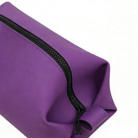 Close-up of purple toiletry bag with black rubberized zipper and contrast stitching, showcasing premium material quality and durable hardware details.